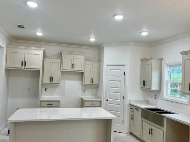 kitchen featuring a center island, crown molding, recessed lighting, visible vents, and a sink