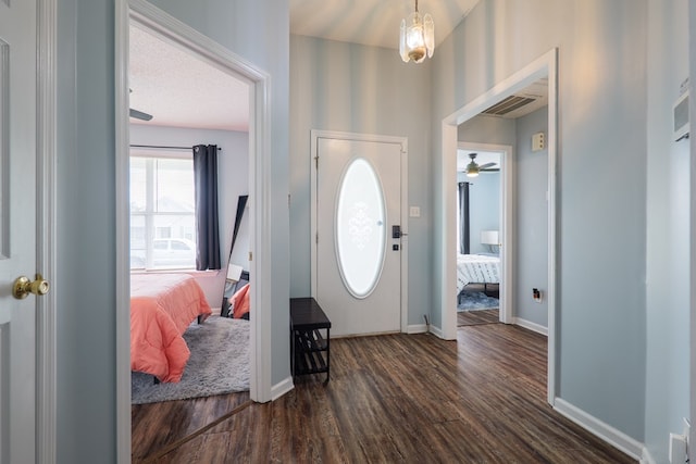 entrance foyer featuring a ceiling fan, visible vents, baseboards, and dark wood-style flooring