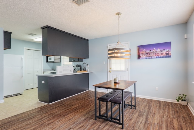 kitchen featuring visible vents, white appliances, light wood-style floors, and a peninsula