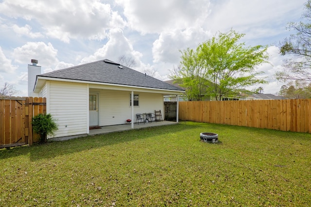 rear view of property with a patio area, a fenced backyard, a lawn, and an outdoor fire pit