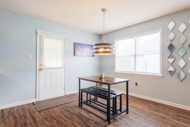 dining room featuring baseboards, a textured ceiling, and wood finished floors