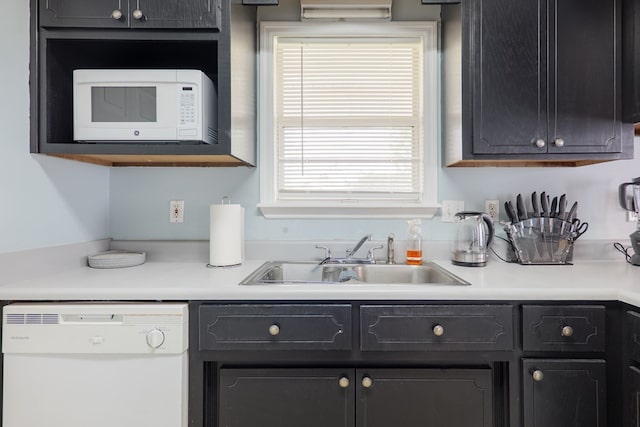 kitchen with white appliances, light countertops, and a sink