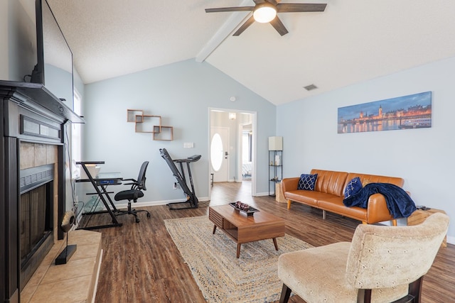 living room with a tiled fireplace, lofted ceiling with beams, a ceiling fan, and wood finished floors