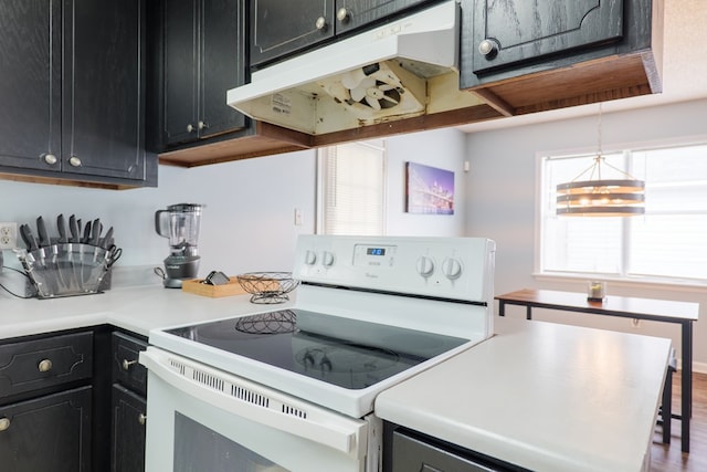 kitchen featuring dark cabinetry, light countertops, electric stove, under cabinet range hood, and pendant lighting