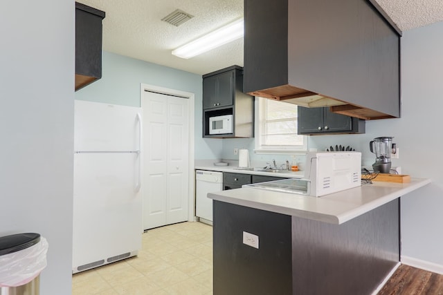 kitchen with visible vents, light countertops, a peninsula, white appliances, and a textured ceiling