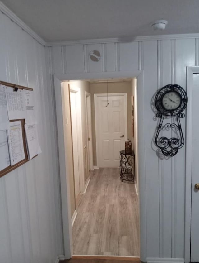 hallway featuring crown molding and light hardwood / wood-style flooring