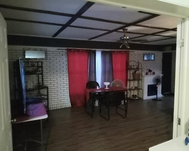 dining space with a fireplace, dark hardwood / wood-style flooring, coffered ceiling, and brick wall