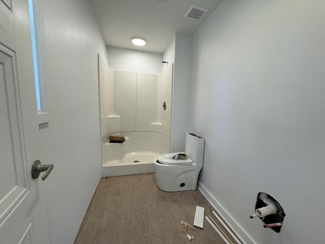 bathroom featuring wood finished floors, baseboards, visible vents, walk in shower, and toilet