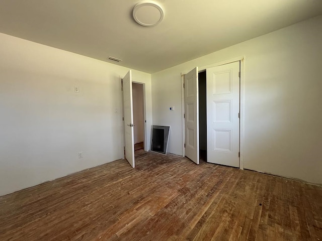 unfurnished bedroom with visible vents and wood finished floors