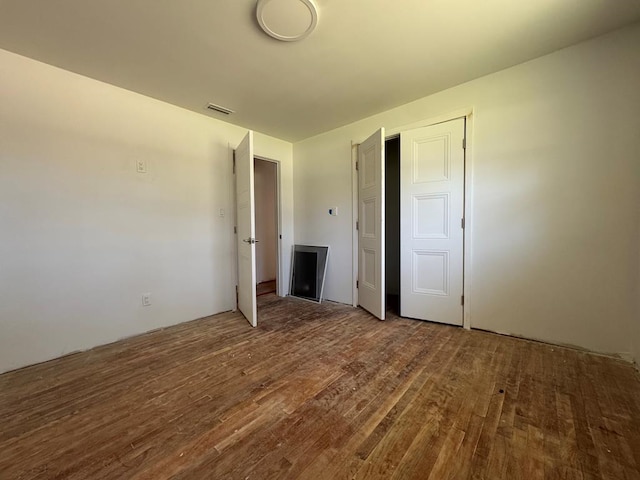 unfurnished bedroom featuring wood finished floors and visible vents