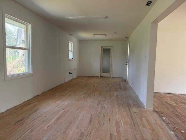 empty room with visible vents, plenty of natural light, and light wood finished floors