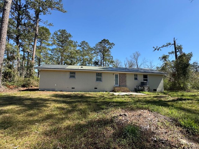 back of property featuring metal roof and a yard