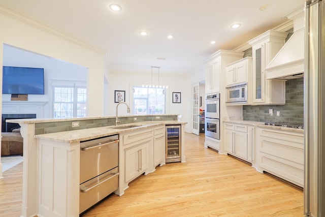 kitchen with pendant lighting, sink, premium range hood, stainless steel appliances, and beverage cooler