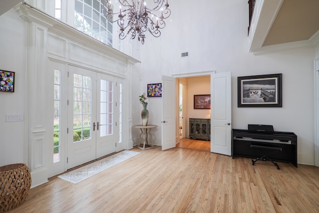 entrance foyer with a high ceiling, light hardwood / wood-style floors, and french doors