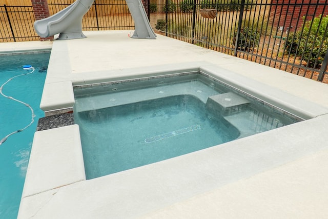 view of swimming pool with a hot tub, a diving board, and a water slide