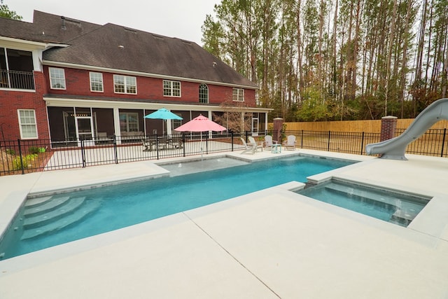 view of pool with an in ground hot tub, a water slide, and a patio