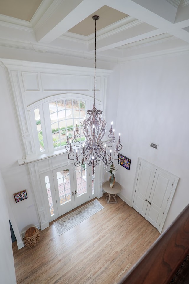 entryway with crown molding, light hardwood / wood-style flooring, and a high ceiling