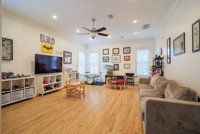 living room with crown molding, ceiling fan, and light wood-type flooring