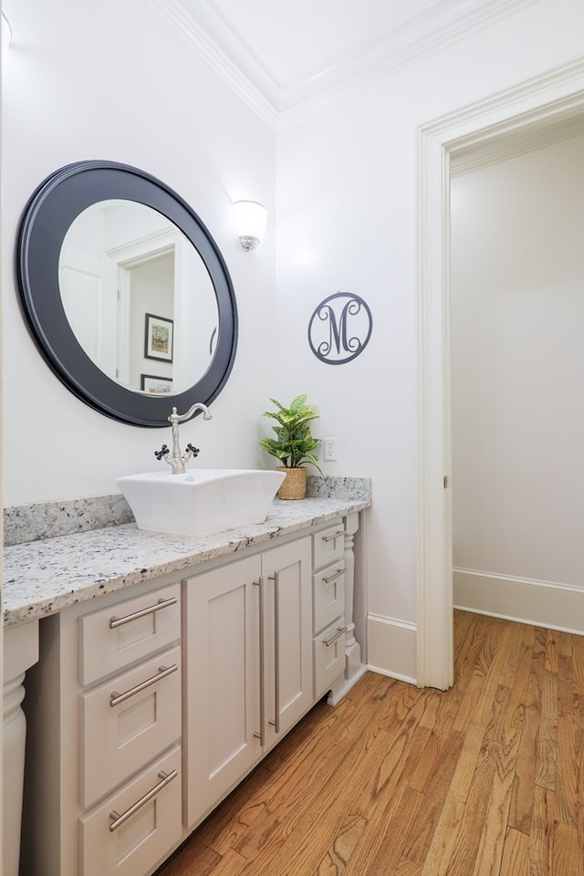 bathroom featuring hardwood / wood-style flooring, crown molding, and vanity