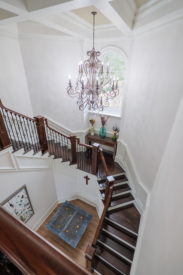 staircase with crown molding, coffered ceiling, hardwood / wood-style floors, and a chandelier