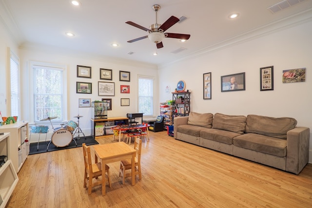 living room with ornamental molding, a wealth of natural light, ceiling fan, and light hardwood / wood-style flooring