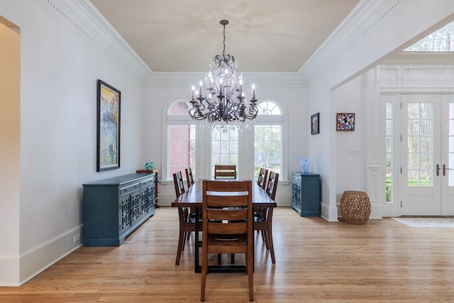 dining room featuring an inviting chandelier, crown molding, light hardwood / wood-style floors, and french doors