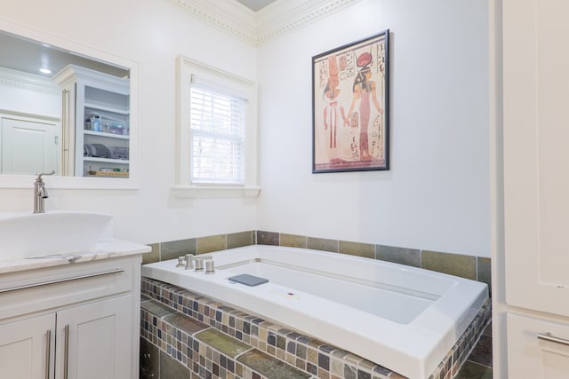 bathroom featuring ornamental molding, vanity, and tiled bath