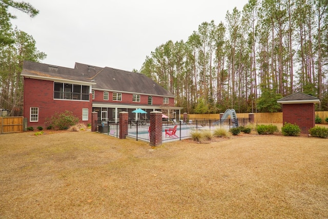 rear view of property featuring a yard and a fenced in pool