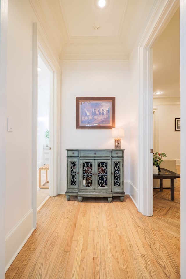 hall with ornamental molding and light hardwood / wood-style floors