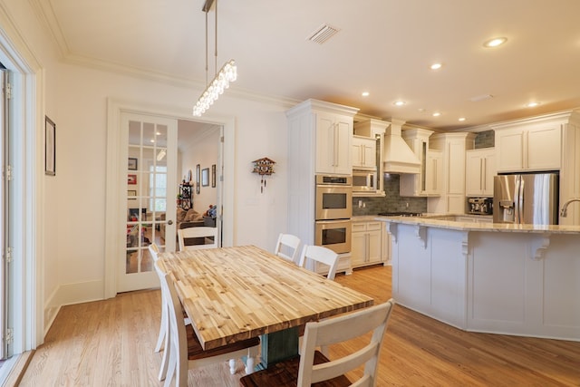 kitchen featuring custom exhaust hood, light stone counters, hanging light fixtures, stainless steel appliances, and white cabinets