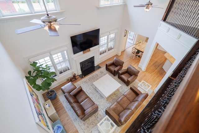 living room with ceiling fan, a towering ceiling, and light hardwood / wood-style floors