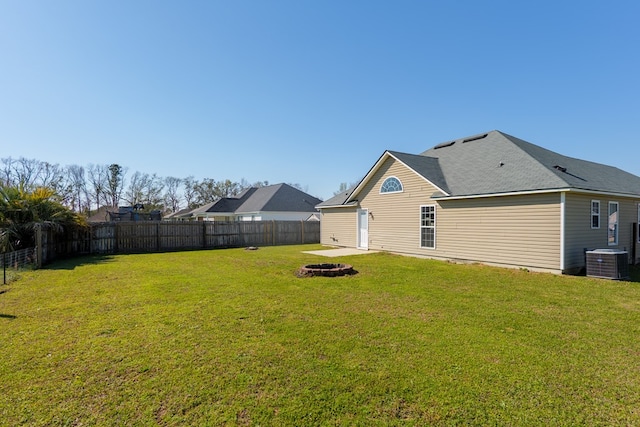 view of yard featuring central air condition unit, a fenced backyard, and an outdoor fire pit