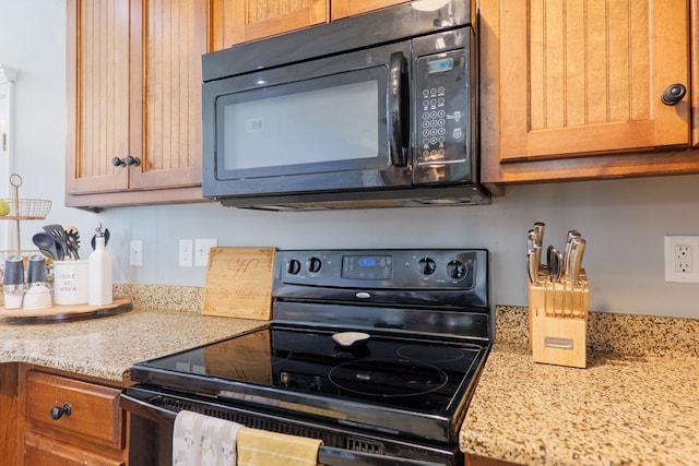 kitchen featuring light stone counters and black appliances