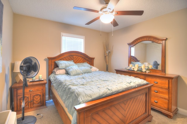 bedroom featuring a textured ceiling, a ceiling fan, baseboards, and light carpet