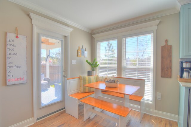 dining space featuring light wood-style flooring, baseboards, and ornamental molding