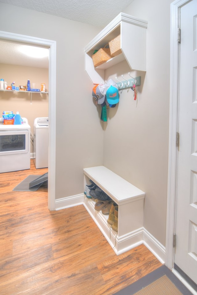 mudroom featuring baseboards, separate washer and dryer, wood finished floors, and a textured ceiling