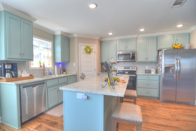 kitchen featuring wood finished floors, visible vents, a sink, stainless steel appliances, and a kitchen breakfast bar