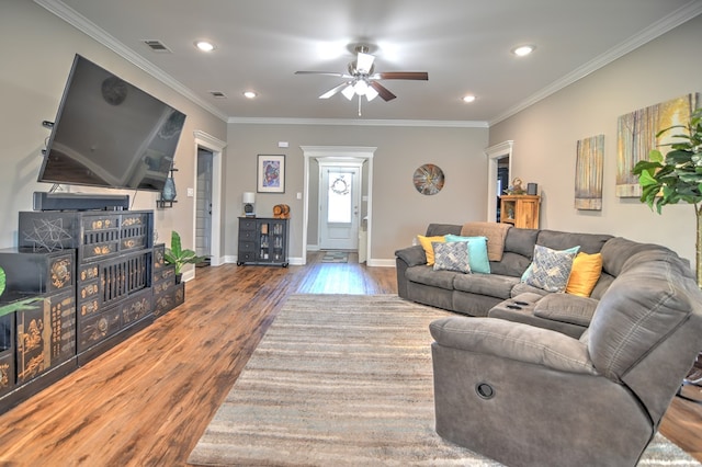 living area with wood finished floors, visible vents, and ornamental molding