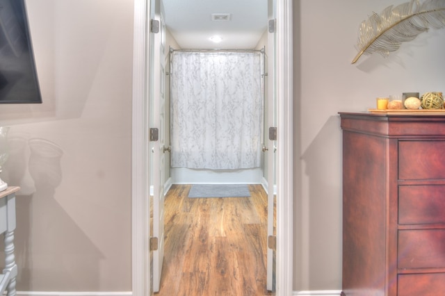 full bath with visible vents, shower / tub combo, baseboards, and wood finished floors