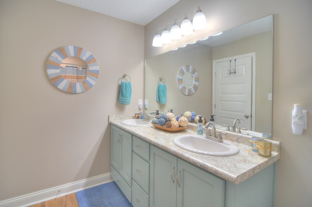 full bath with double vanity, baseboards, and a sink