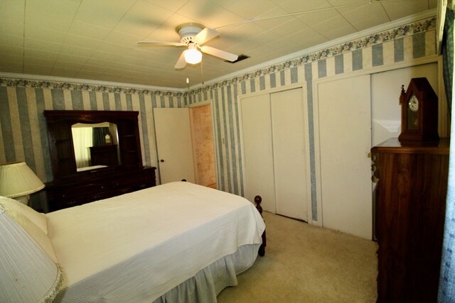 carpeted bedroom featuring ceiling fan, two closets, and ornamental molding