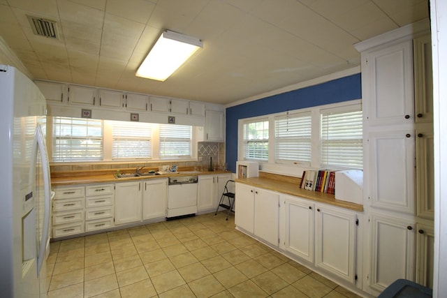 kitchen featuring tasteful backsplash, white appliances, sink, white cabinets, and light tile patterned flooring