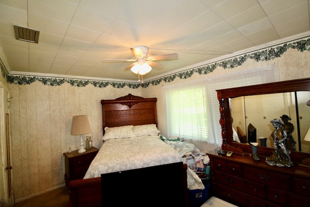 bedroom featuring crown molding, ceiling fan, and wooden walls