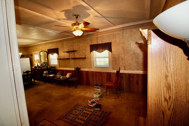 carpeted living room featuring ceiling fan and wooden walls