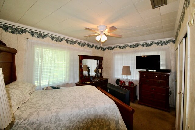 carpeted bedroom featuring ceiling fan and crown molding