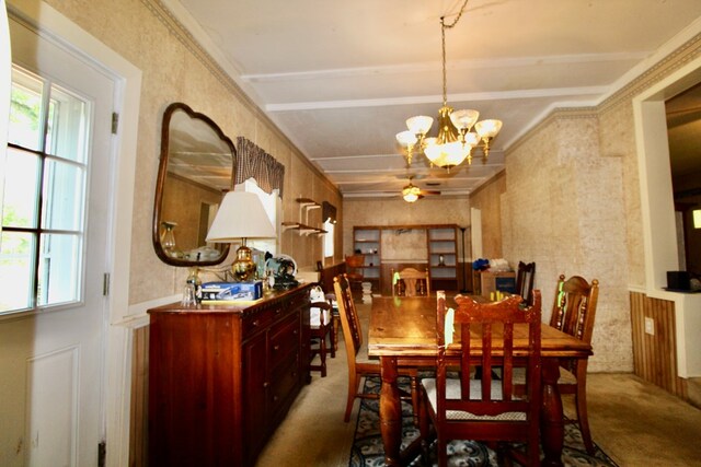 carpeted dining space featuring ceiling fan with notable chandelier and ornamental molding