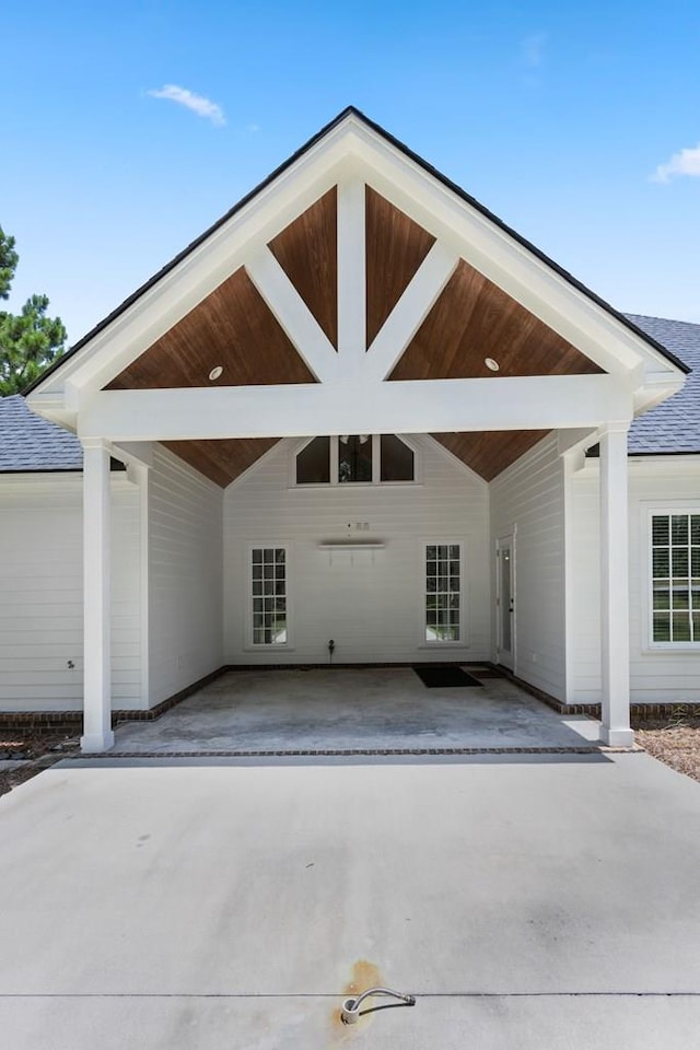 exterior space with a carport, concrete driveway, and a shingled roof