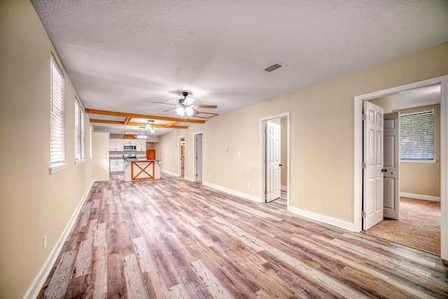 unfurnished living room with baseboards, a healthy amount of sunlight, visible vents, and light wood-style floors