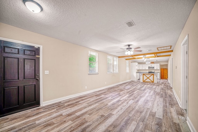 unfurnished living room with ceiling fan, light wood finished floors, visible vents, and baseboards