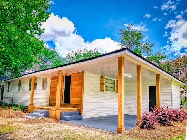 view of front facade featuring a carport, a porch, a patio area, and driveway